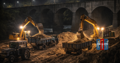 Excavators load sand into tractors during a nighttime sand mining operation near a river and railway bridge, illustrating illegal sand extraction activities in Mortad mandal.