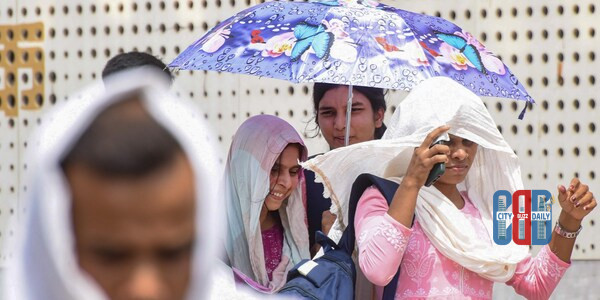 Scorching sunlight over a dry landscape in western India during a heat wave while dark rain clouds gather over northeastern hills.